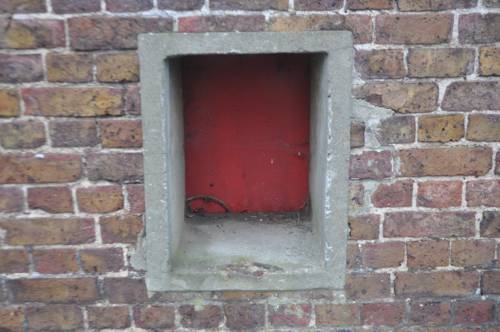 Fire door in asylum wall, Hanwell Locks A square red door recessed in a thick brick wall