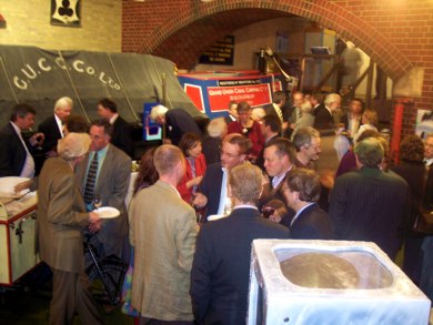 People standing at a party with red boat and brick arch behind
