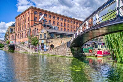 Angled footbridge over the canal at Camden, large brick buiding behind.